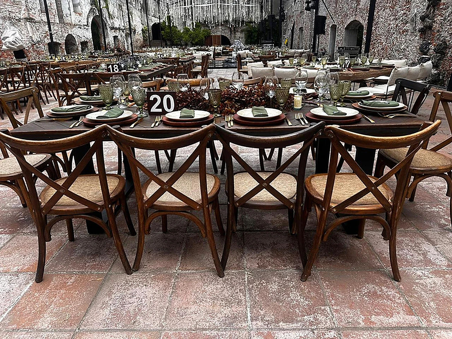 Banquete largo montado en patio de cantera con sillas cross-back